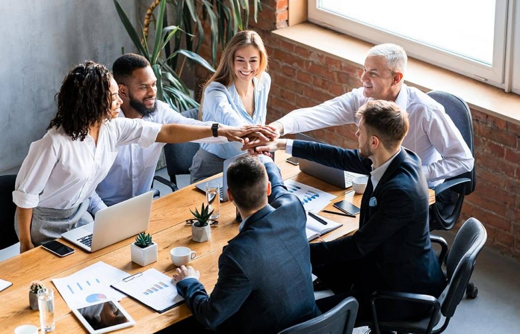 united business team holding hands sitting togethe 7YNV6QS